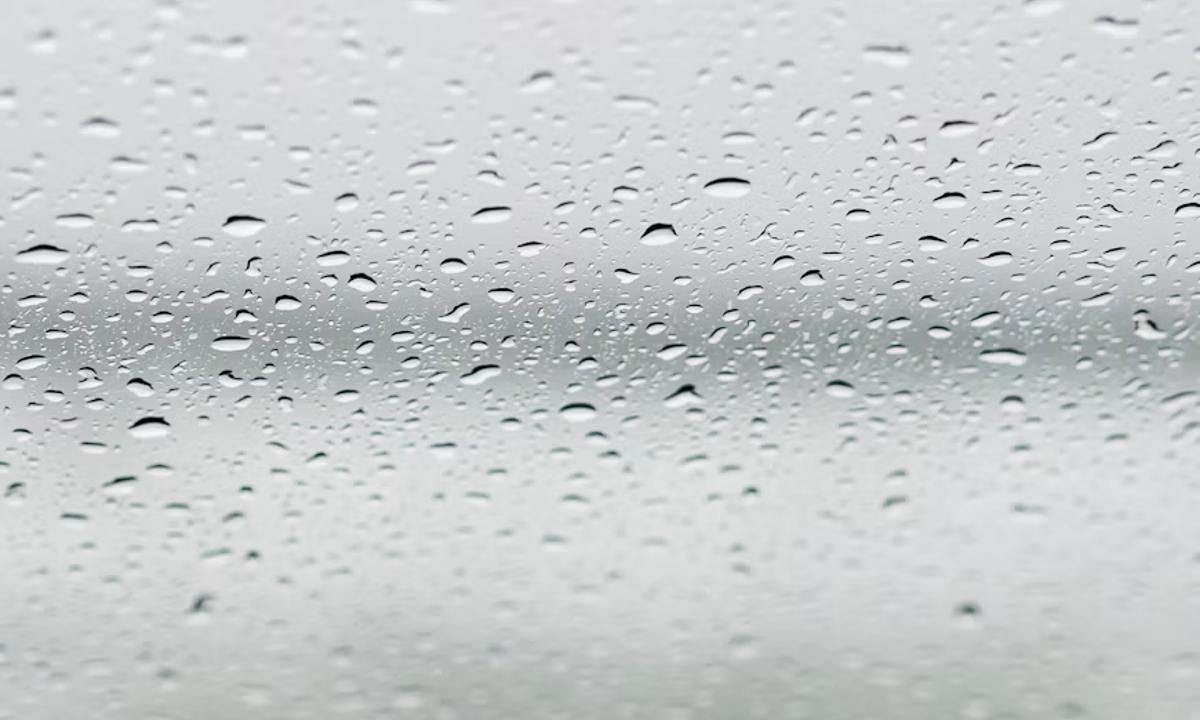 Краплі води на склі з розмитим краєвидом за ним